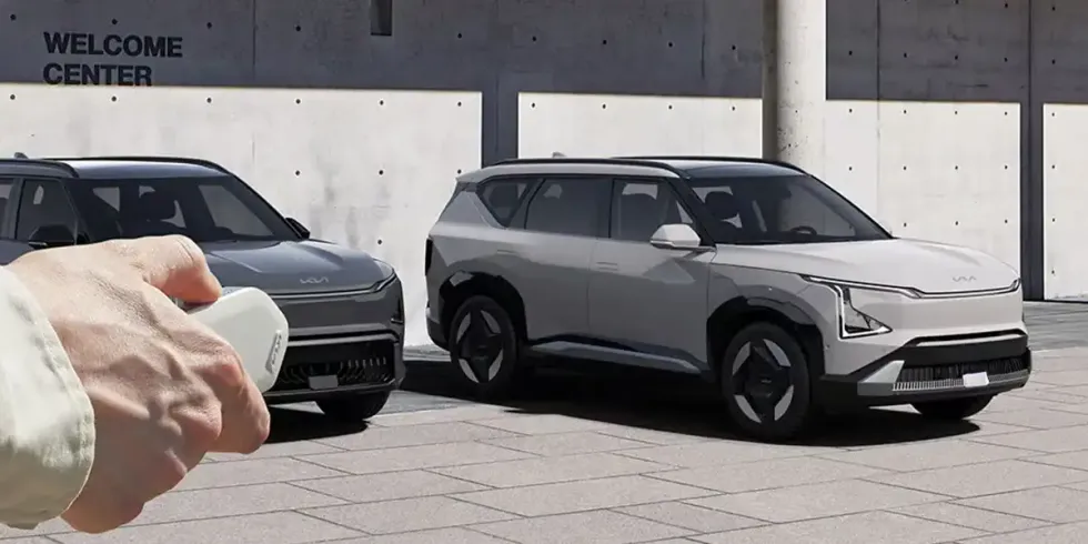 A hand using the Kia EV5 key fob to remotely manouevre the electric SUV into a parking spot.