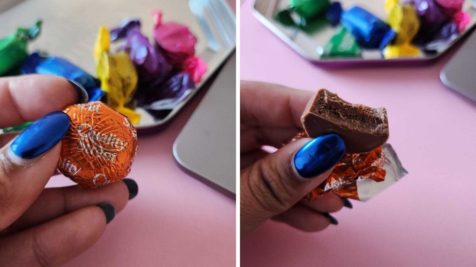 A hand with blue nails holding a chocolate in an orange wrapper. Right: A hand with blue nails holding a chocolate with a bite taken out of it.