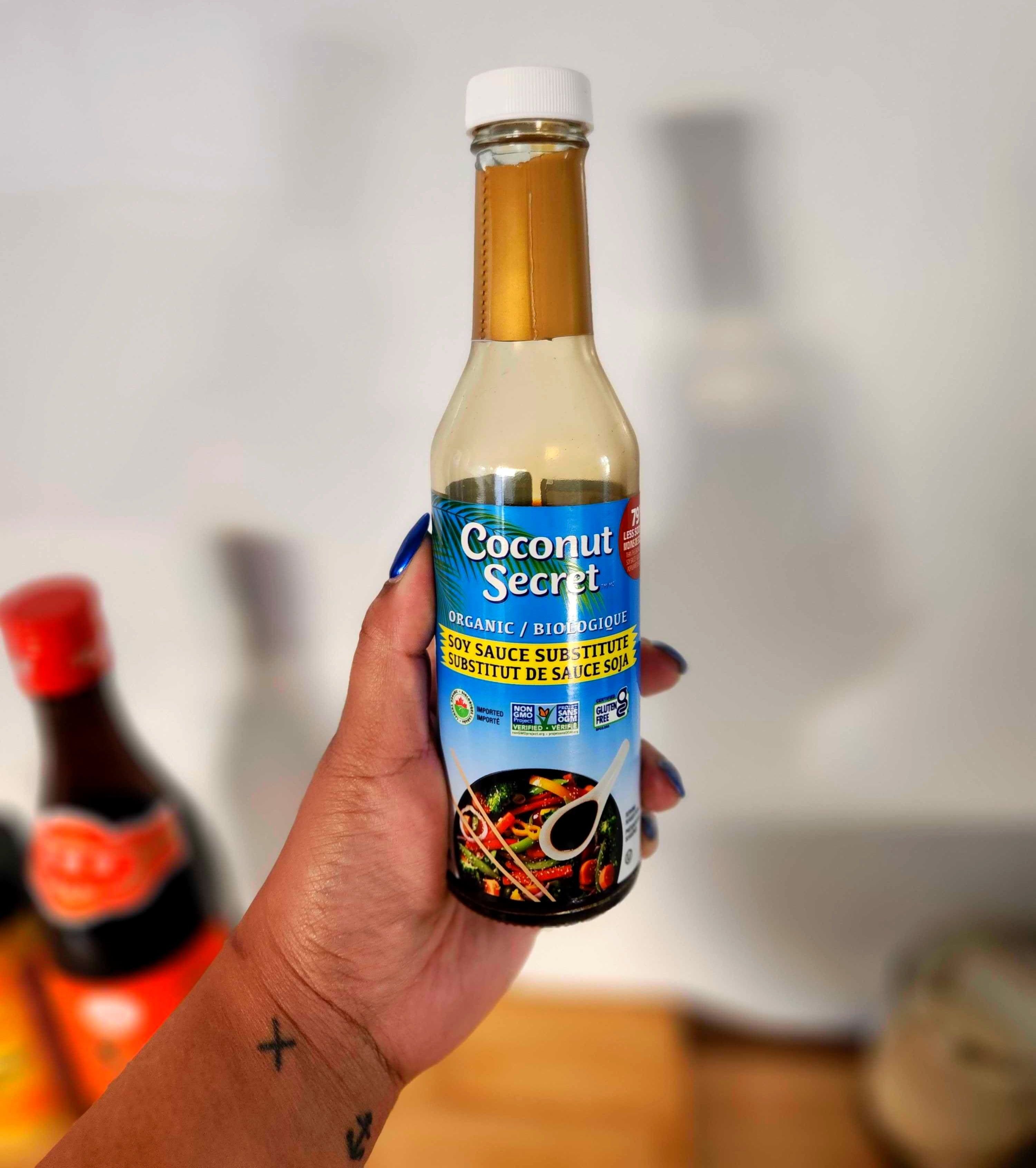 A hand with tattoos golding a clear bottle.