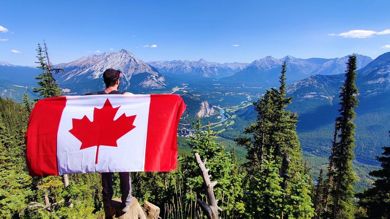 A hiker holding a Canadian flag.