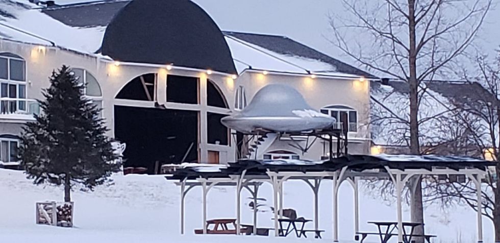 A hotel with a flying saucer in front of it during winter.
