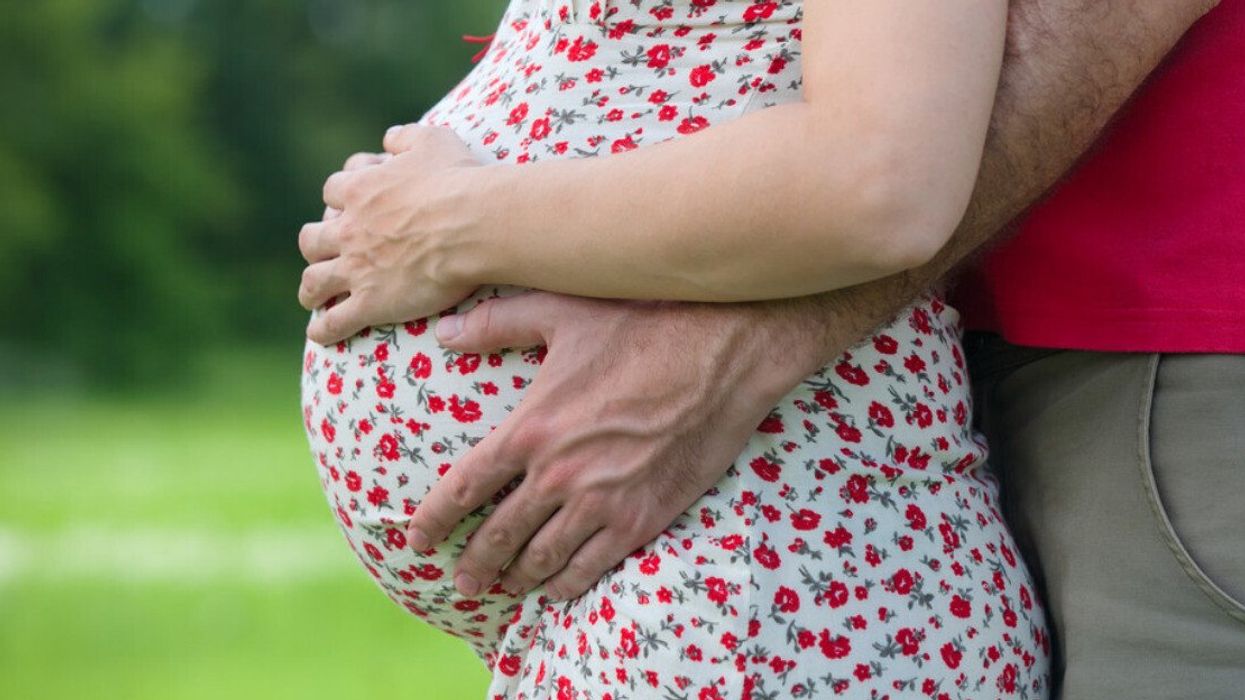 A husband holding his wife's pregnant belly.