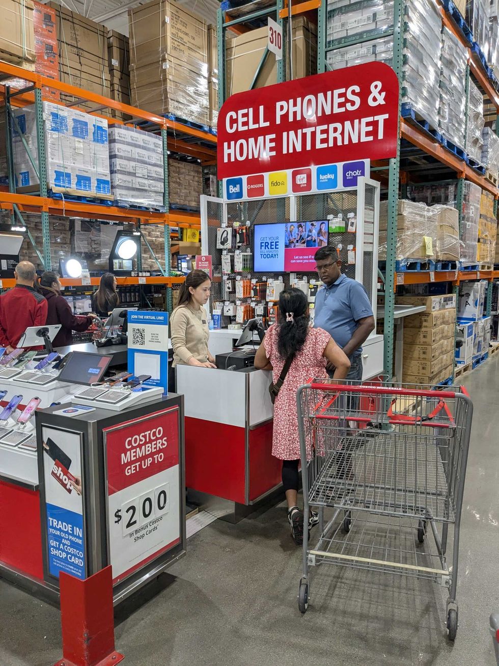 A kiosk at Costco with someone helping customers with their cell phone plans