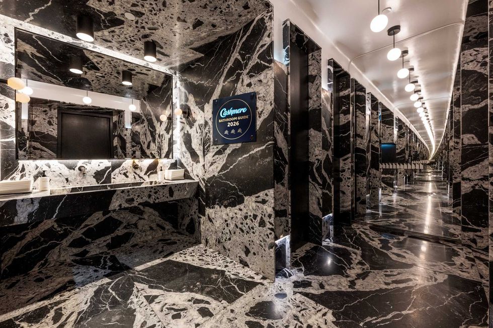 A large, dramatic restuarant bathroom with dark stone floor and walls.