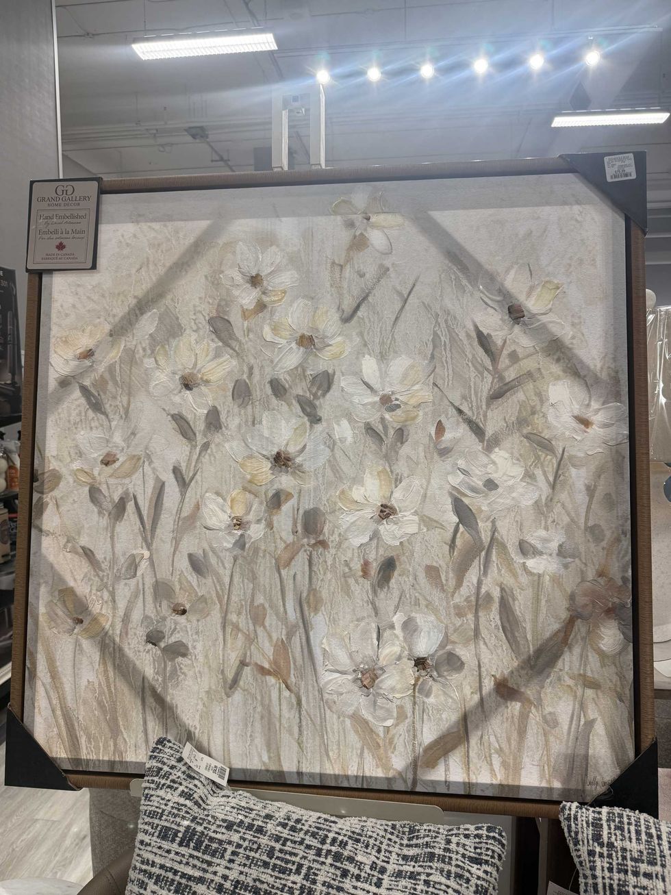 A large piece of artwork of flowers in beige, white and grey tones.