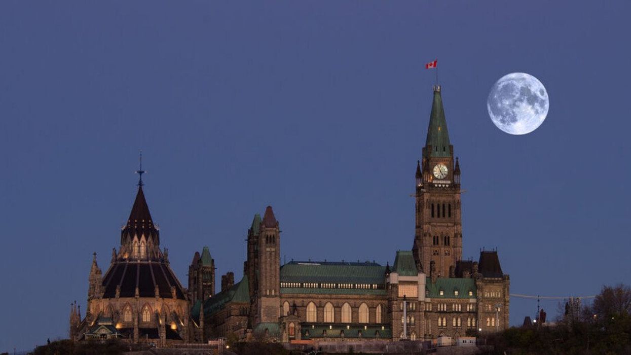 A large supermoon in the sky over parliament buildings.
