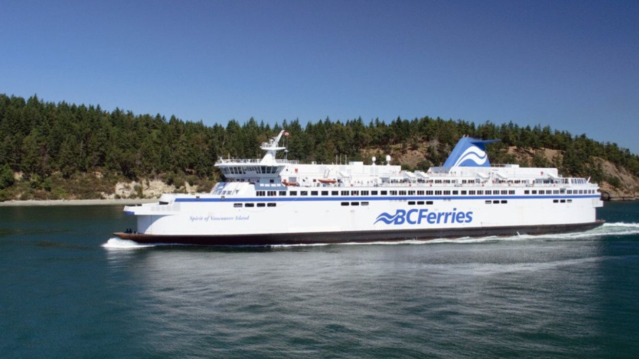 A large white ship that says BC Ferries on it passing an island filled with trees.
