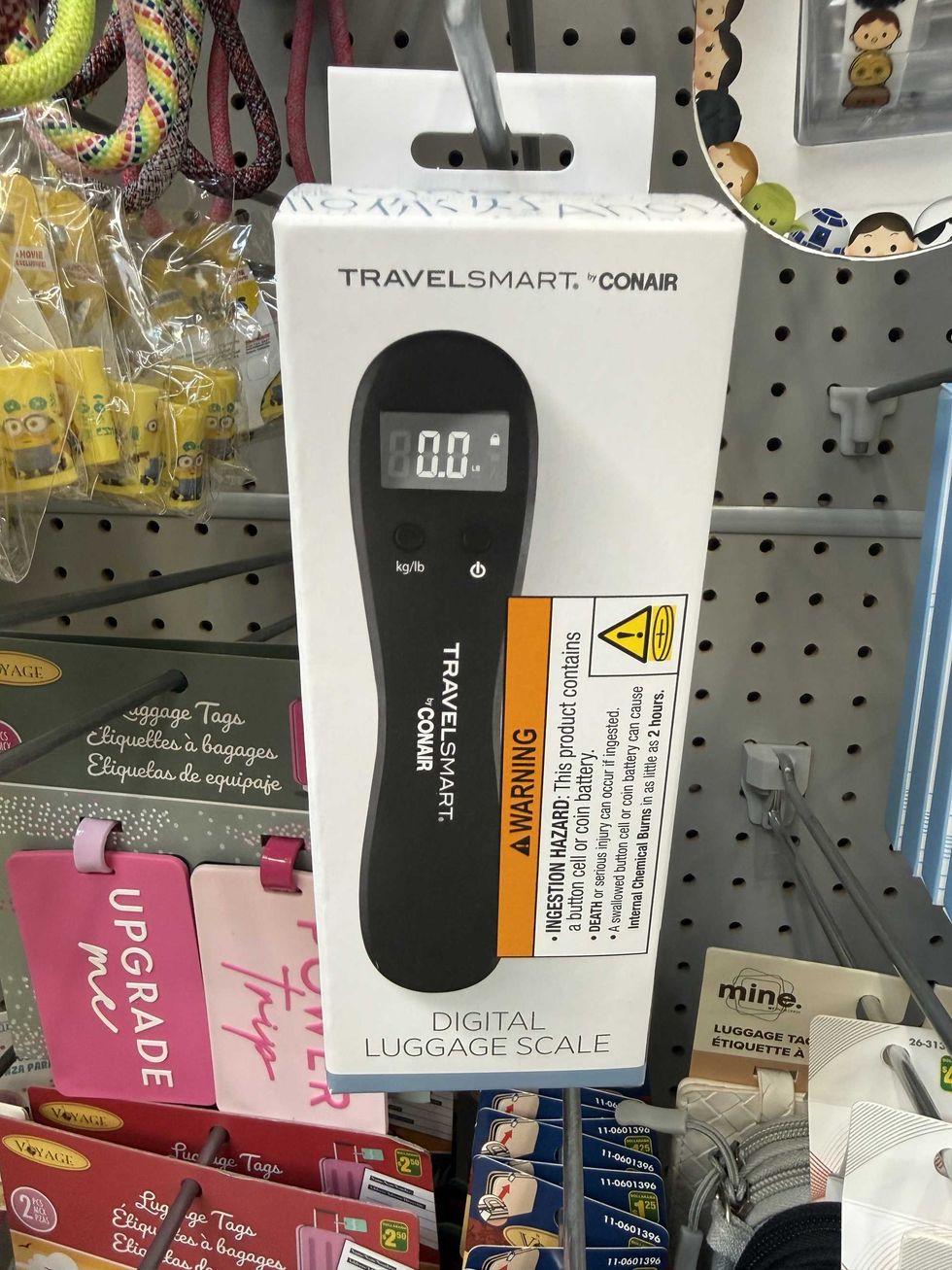 A long black device that has a small screen on it inside of a white box that says digital luggage scale on the front.