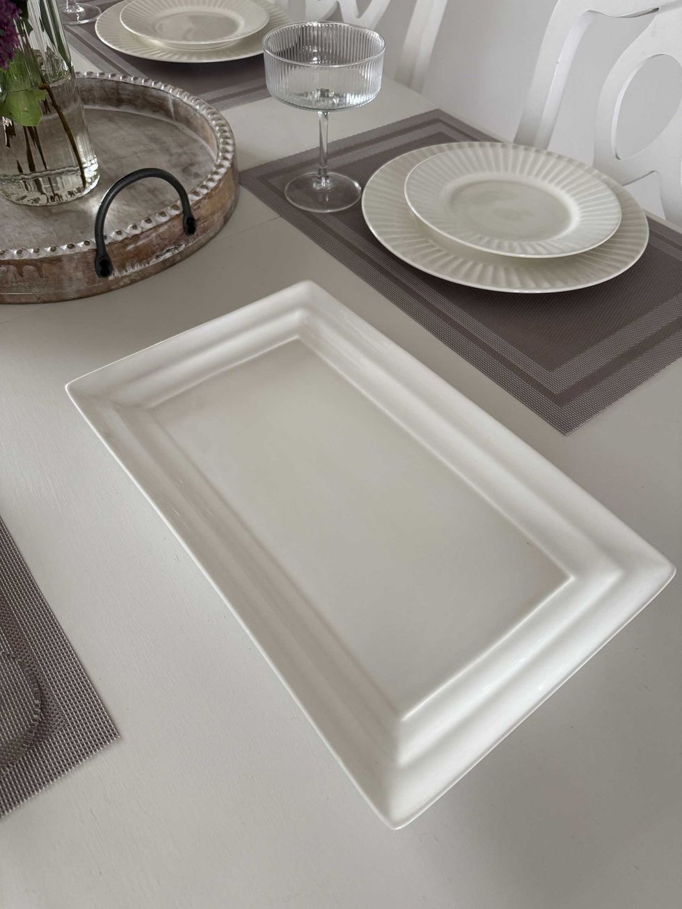 A long, white dish sitting on a white dining table.