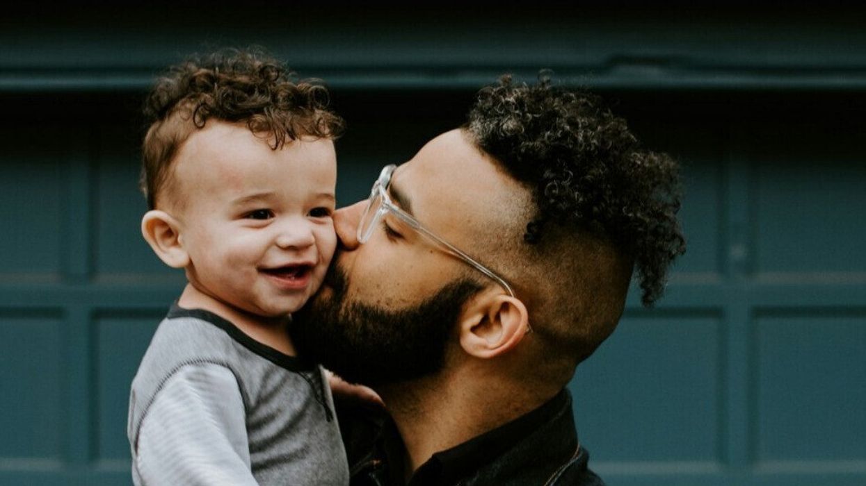 A loving father kisses his smiling toddler on the cheek, capturing a joyful moment of paternal bonding.