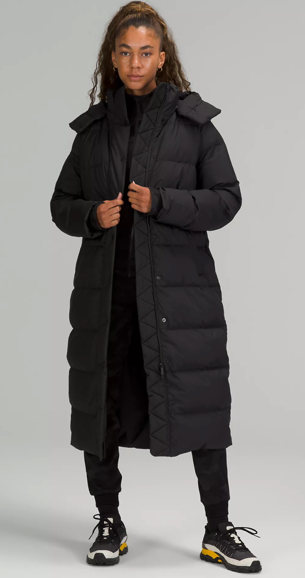 A Lululemon model wearing the Wunder Puff Long Jacket in Black.