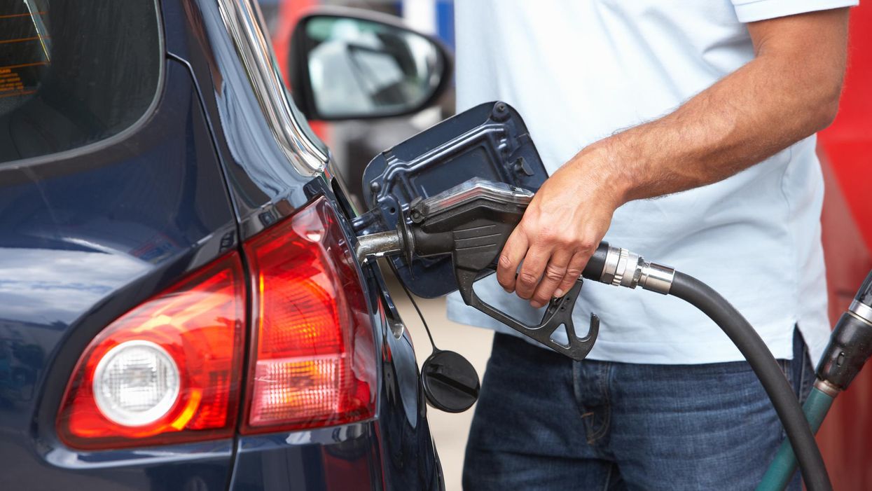 A man fills up his car with gas at a gas station.