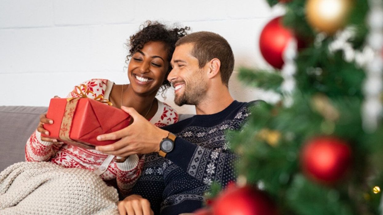 A man giving his girlfriend a Christmas gift.