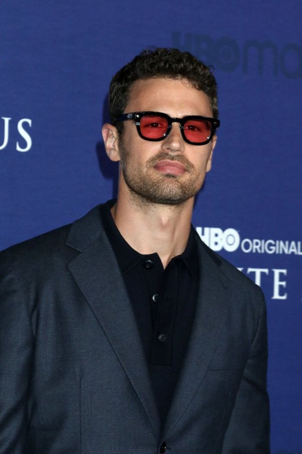 A man in a dark suit wearing sunglasses and looking off camera.