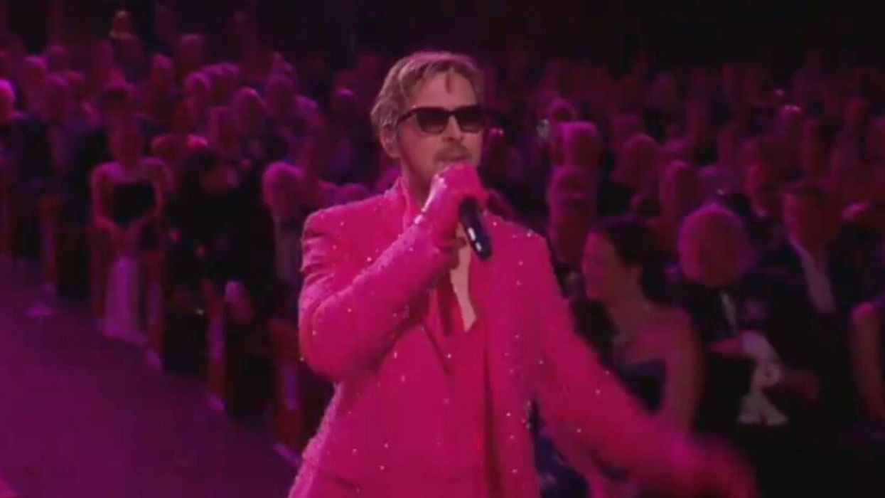 A man in a pink suit singing into a microphone.