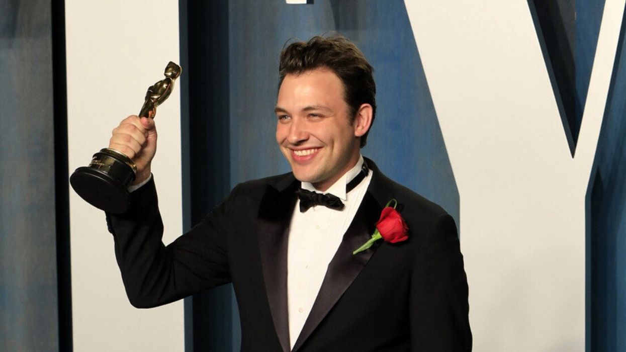 A man in a suit holding up a gold statue.