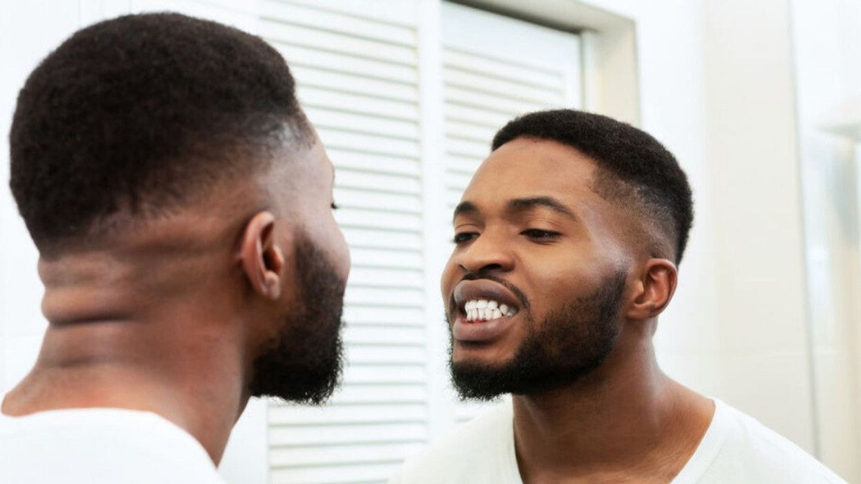 A man looking at his teeth in a mirror.