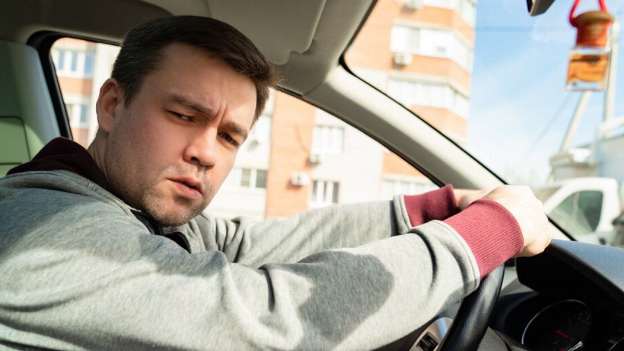 A man looking sad behind the wheel of a car.