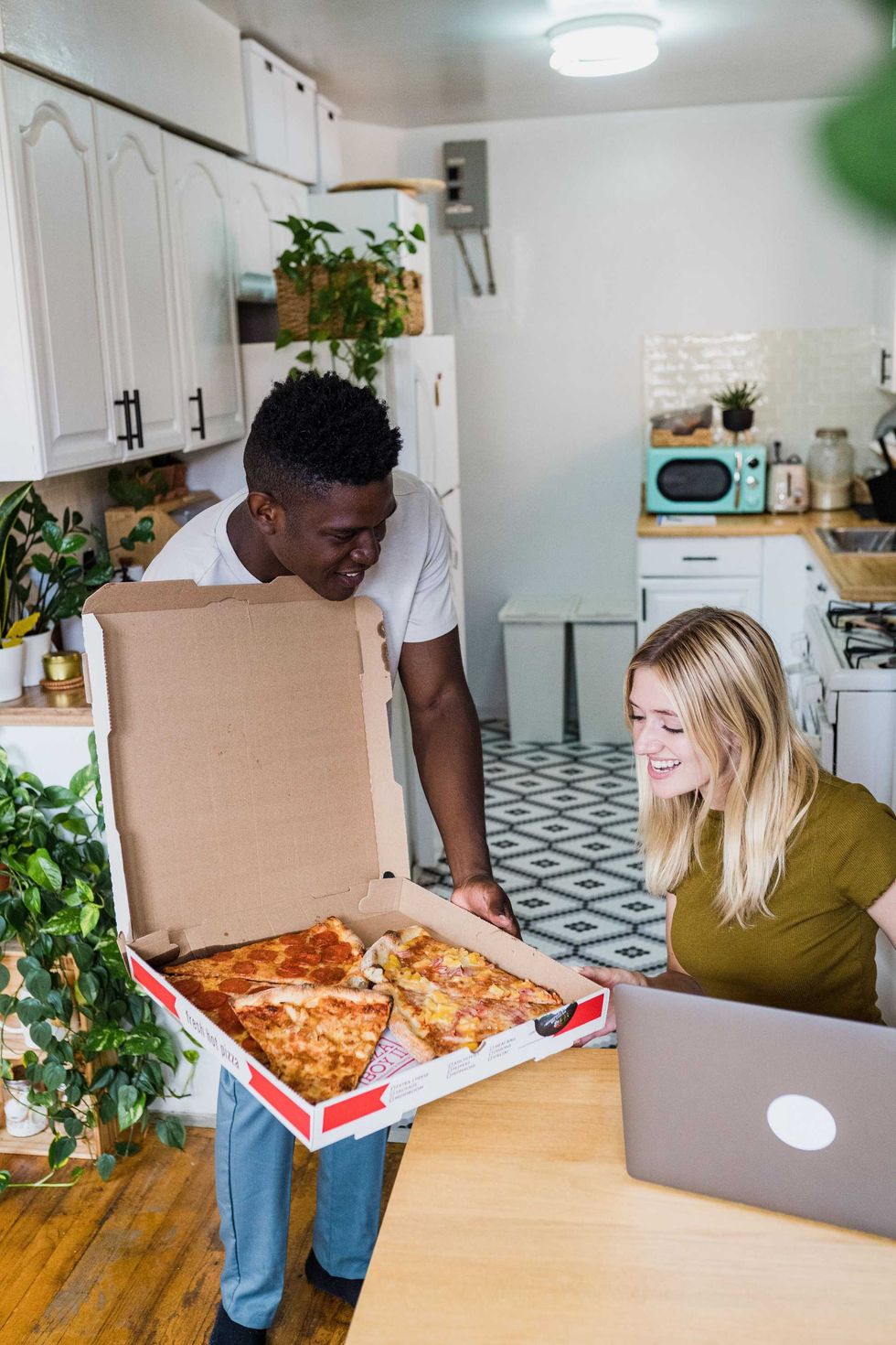 A man offers his roommate pizza.
