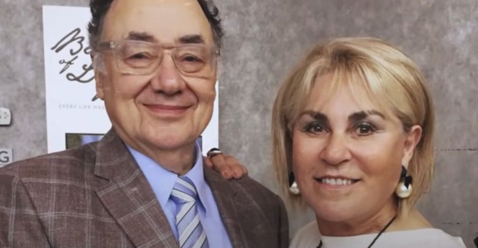 A man with glasses wearing a suit and tie and a woman with short blonde hair smiling for a photo.