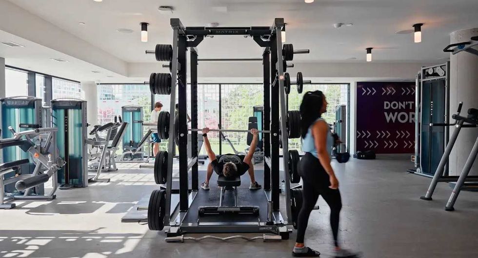 A man works out in the free weights area of a gym.