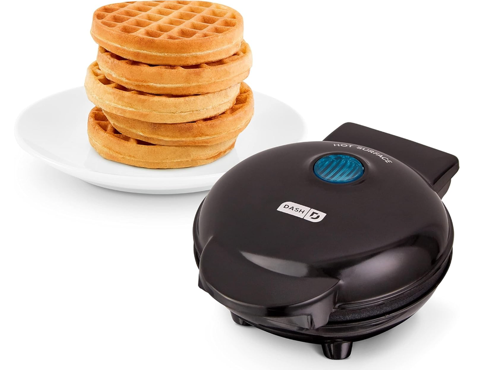 A mini waffle maker with a plate of waffles next to it.