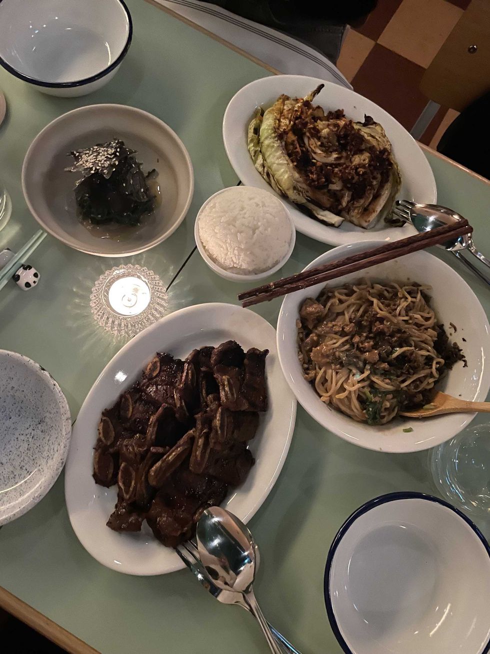 A mint table top with charred cabbage, saut\u00e9ed spinach, short ribs, and dan dan noodles.