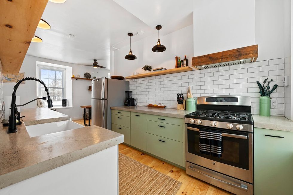 A modern kitchen with green cupboards.