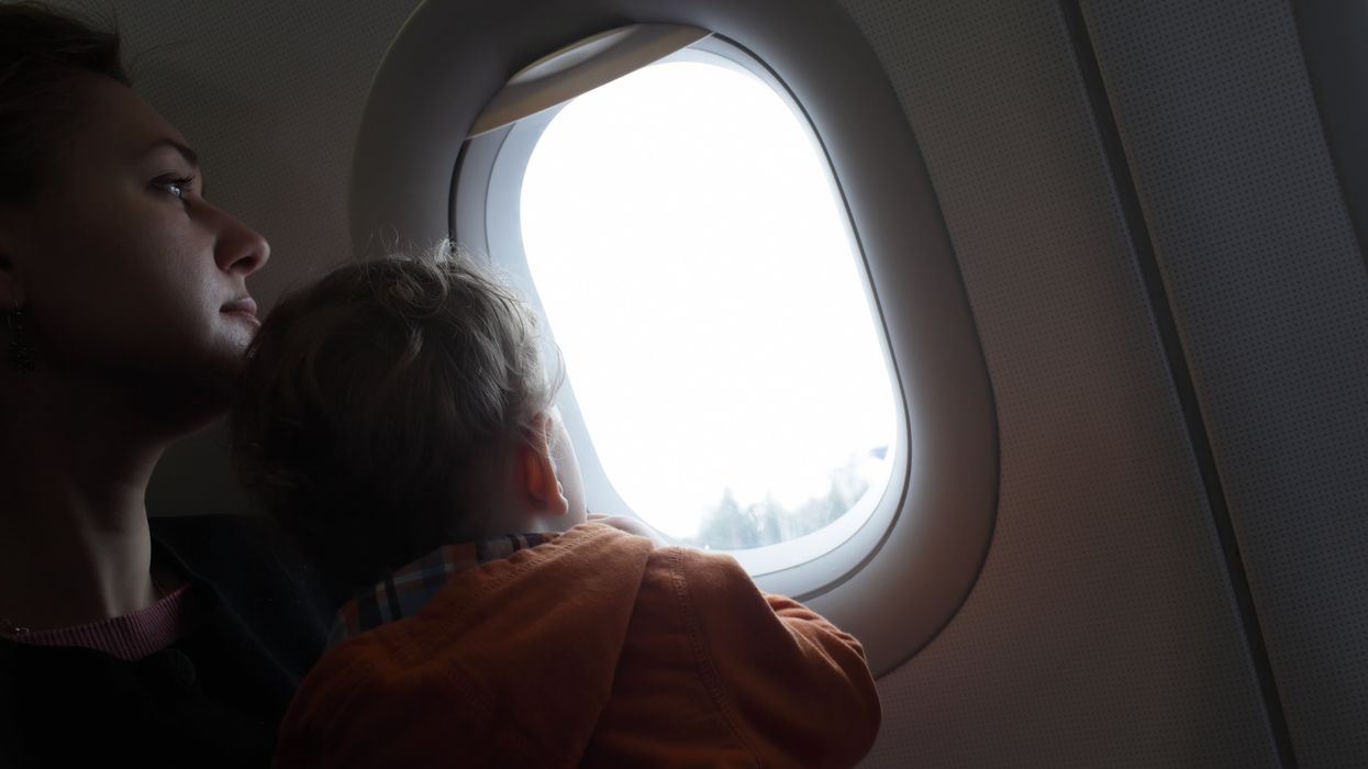A mom and her child looking out a plane window.