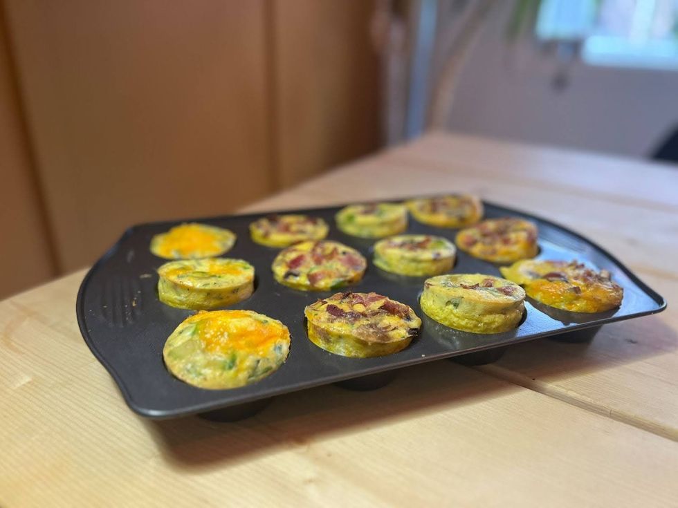 A muffin tray with baked egg cups sitting on a table.