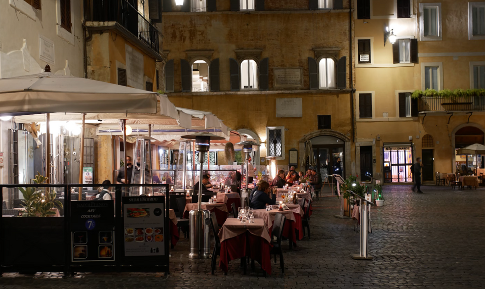 A nice terrace at night with people enjoying their Italian pasti in Rome.