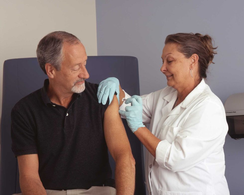 A nurse administers a vaccine into a patient's arm as he watches.