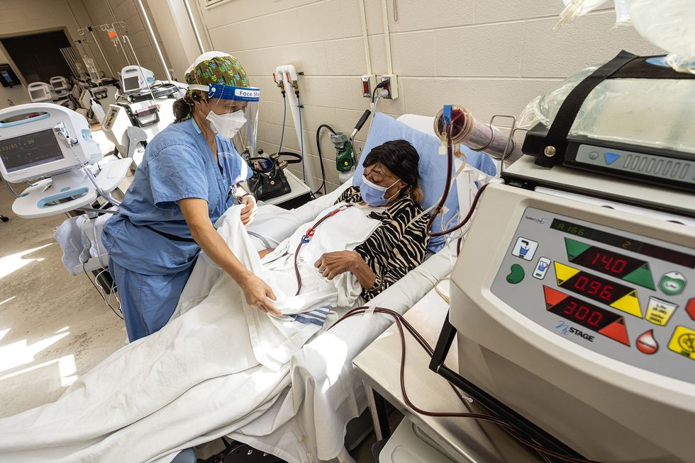 A nurse helps tuck in a patient who is receiving treatment in the hospital.