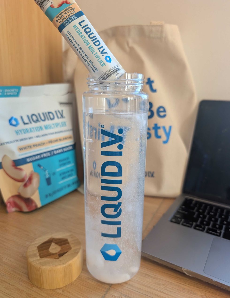 A pack of Liquid I.V. Sugar-Free White Peach being sprinkled into a Liquid I.V. water bottle.