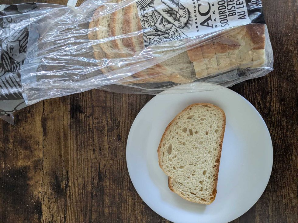 A package of No Frills sourdough bread and a piece of bread on a plate beside it