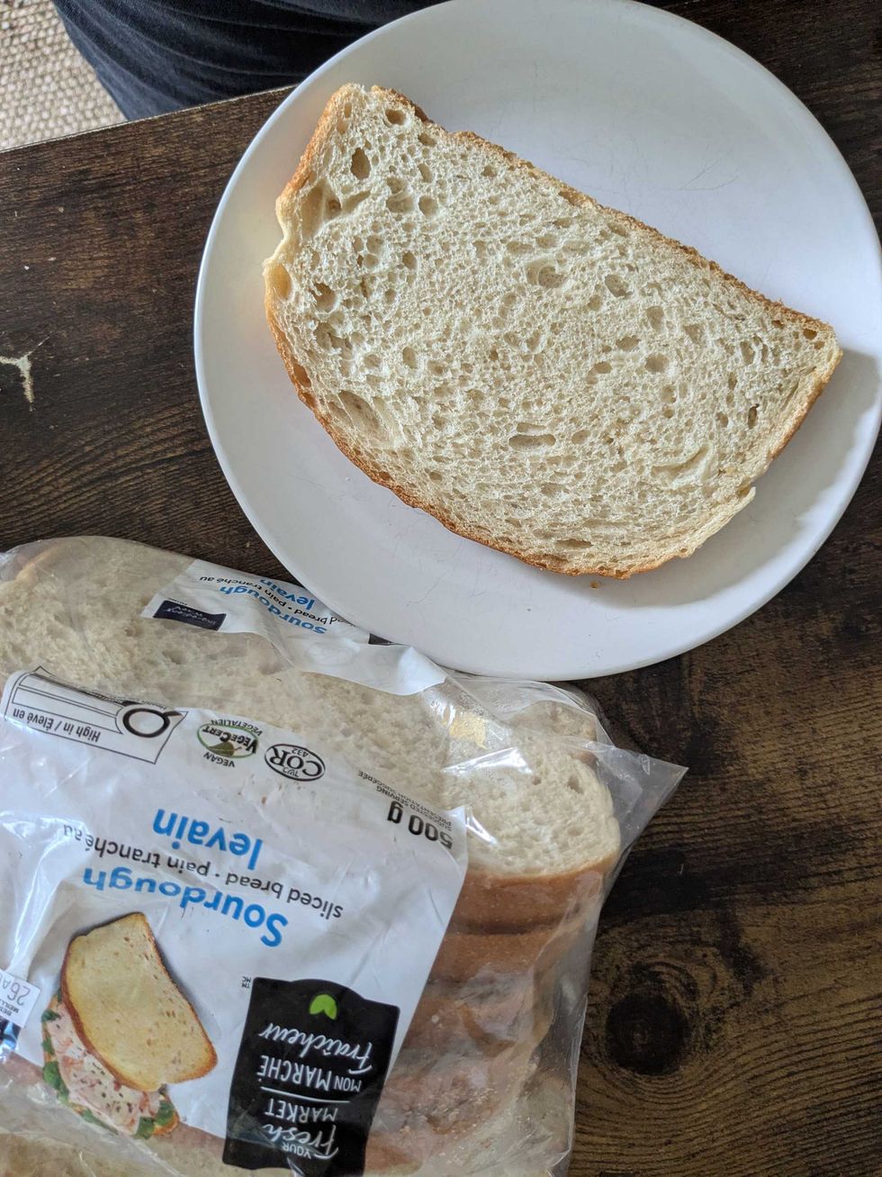 A package of Walmart sourdough bread and a piece of bread on a plate beside it