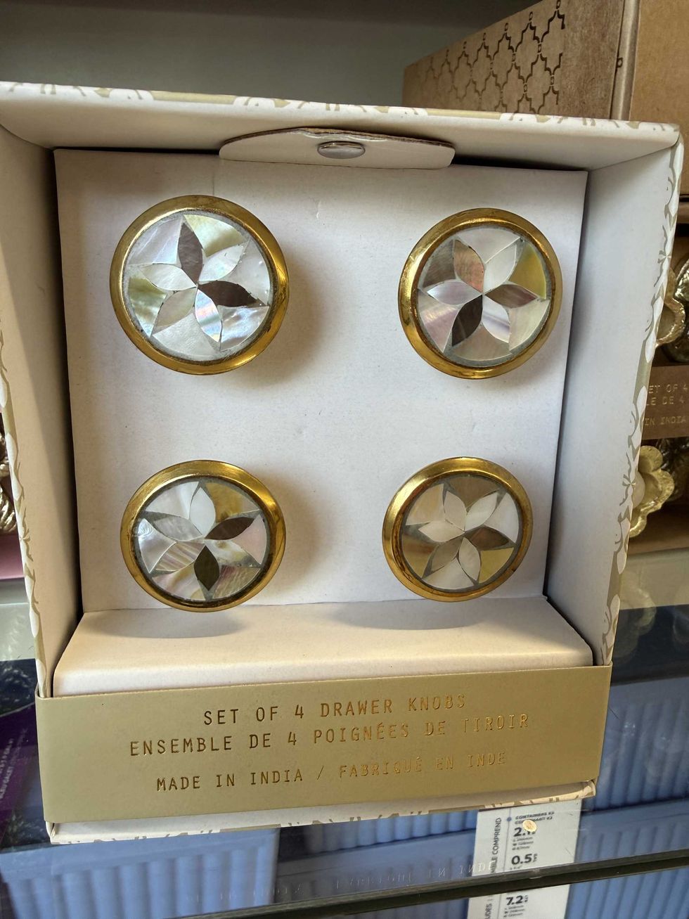 A package with four round items with flower-like designs and a label that reads set of 4 drawer knobs.