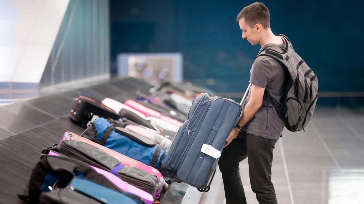 A passenger getting his bag from baggage claim at an airport.
