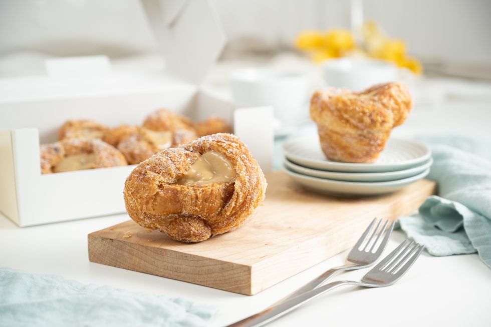 A pastry with caramel filling on a wood chopping board.