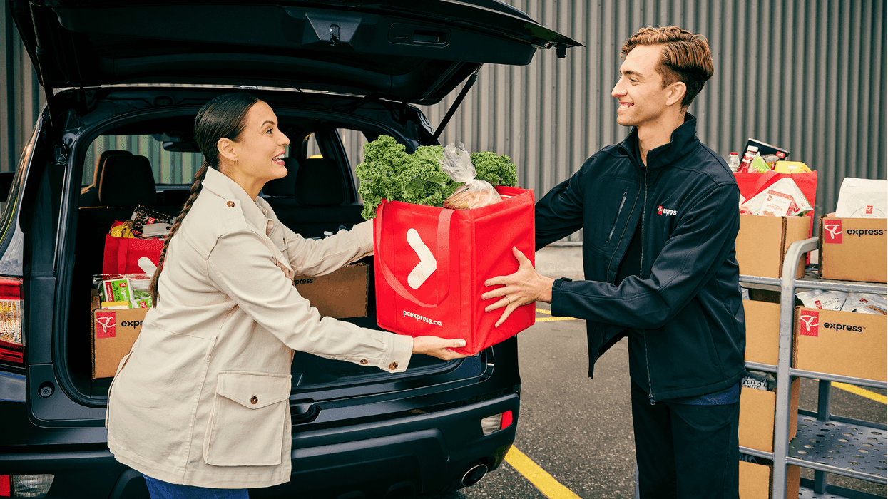 A PC Express employee helps a customer load their car with groceries.