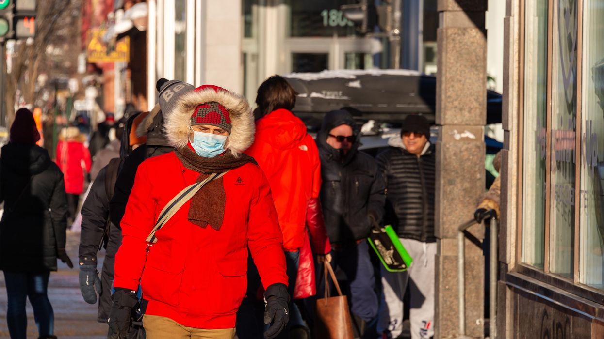 A pedestrian wears a mask while walking down the street.