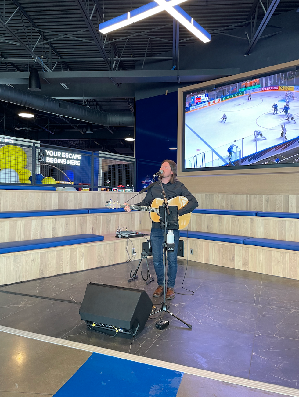 A perfomer singing and playing guitar at Cineplex Junxion.