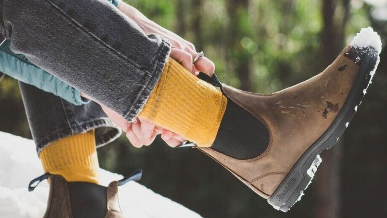 A person adjusting their Blundstones in the snow.