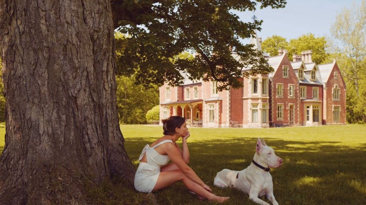 A person and a dog sitting by a historic house.