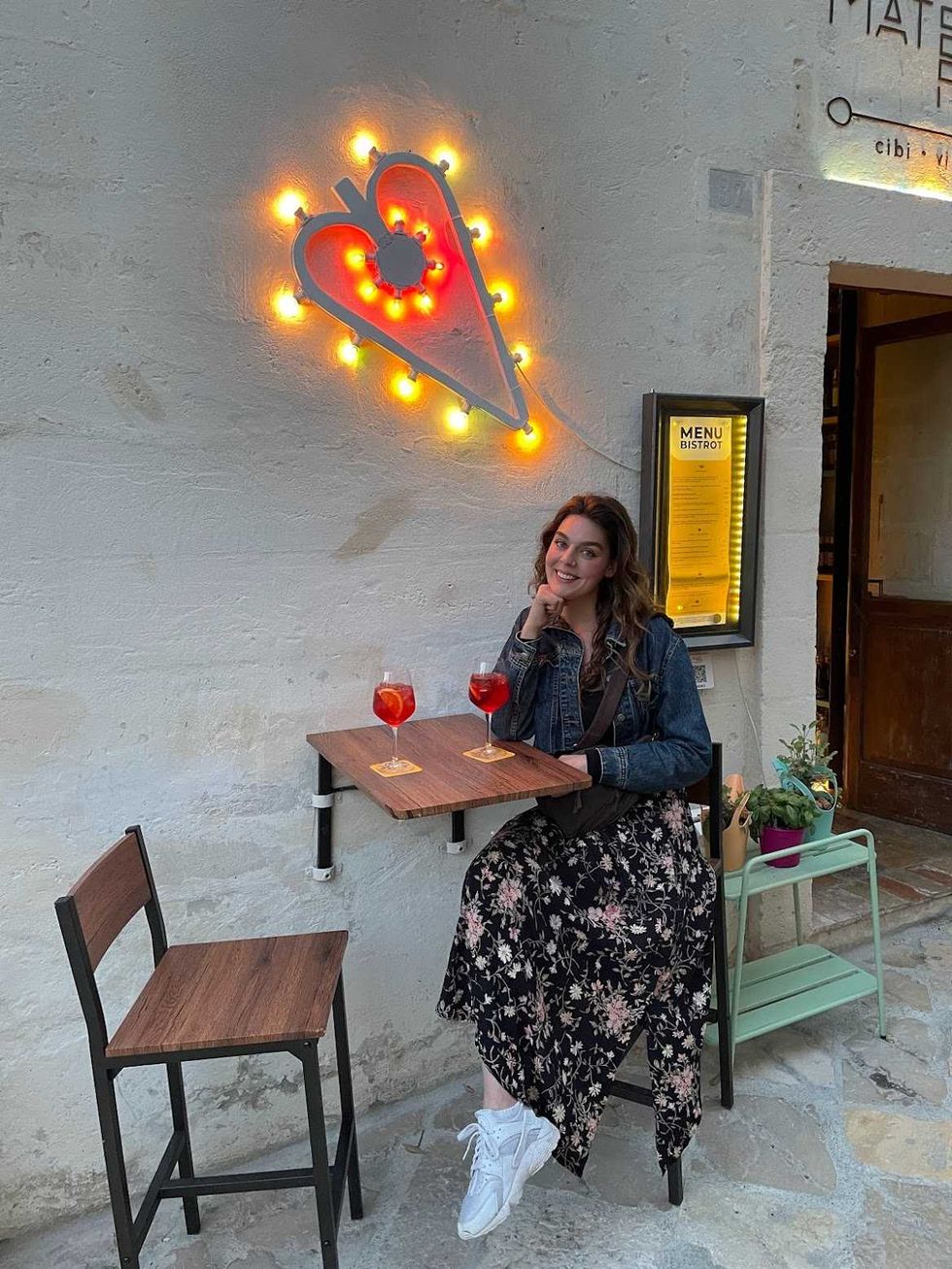 A person at a small table with two drinks.