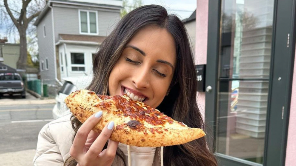 A person biting into a slice of pizza.