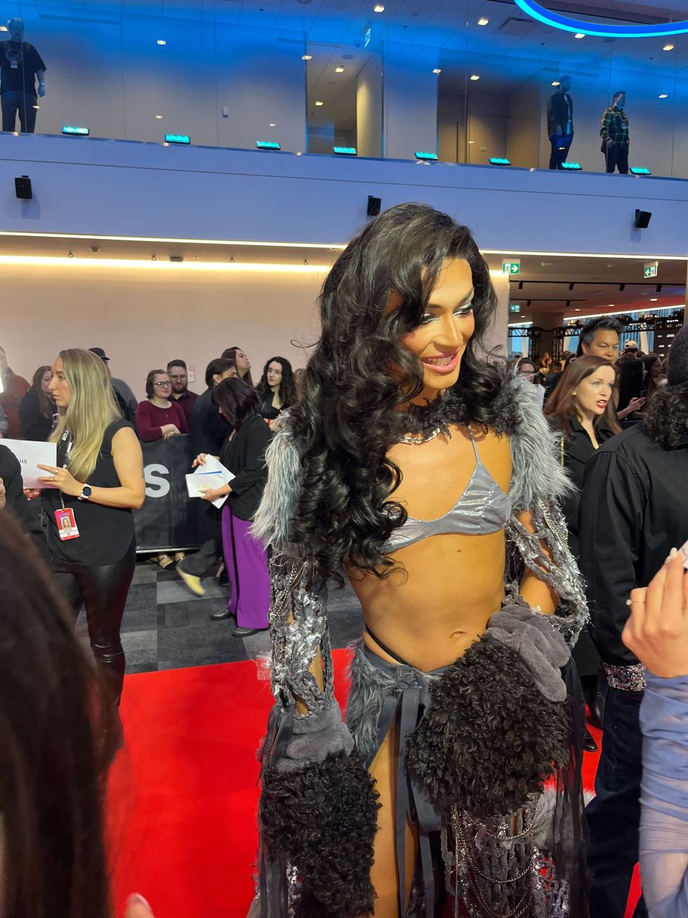 A person dressed in a grey outfit with a silver bikini top during an interview.