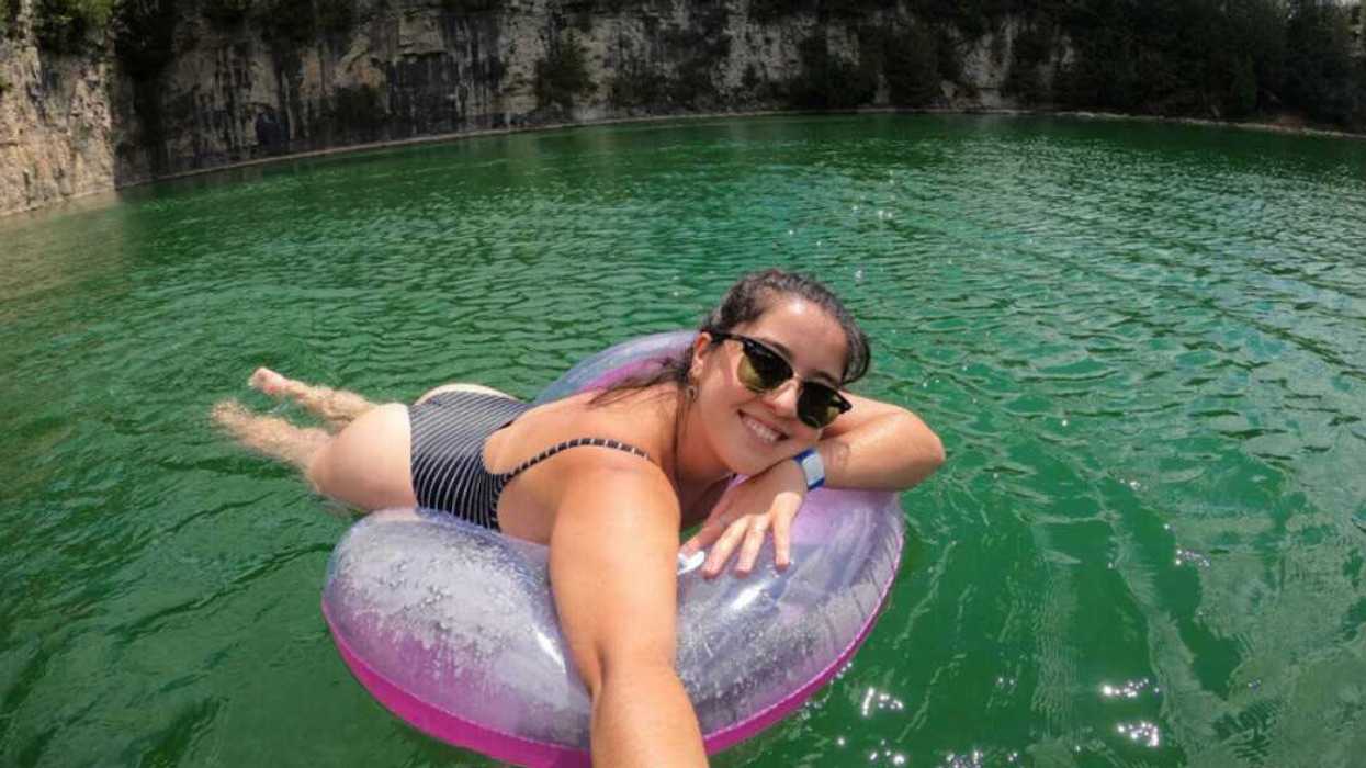 A person floating in a turquoise pool of water.