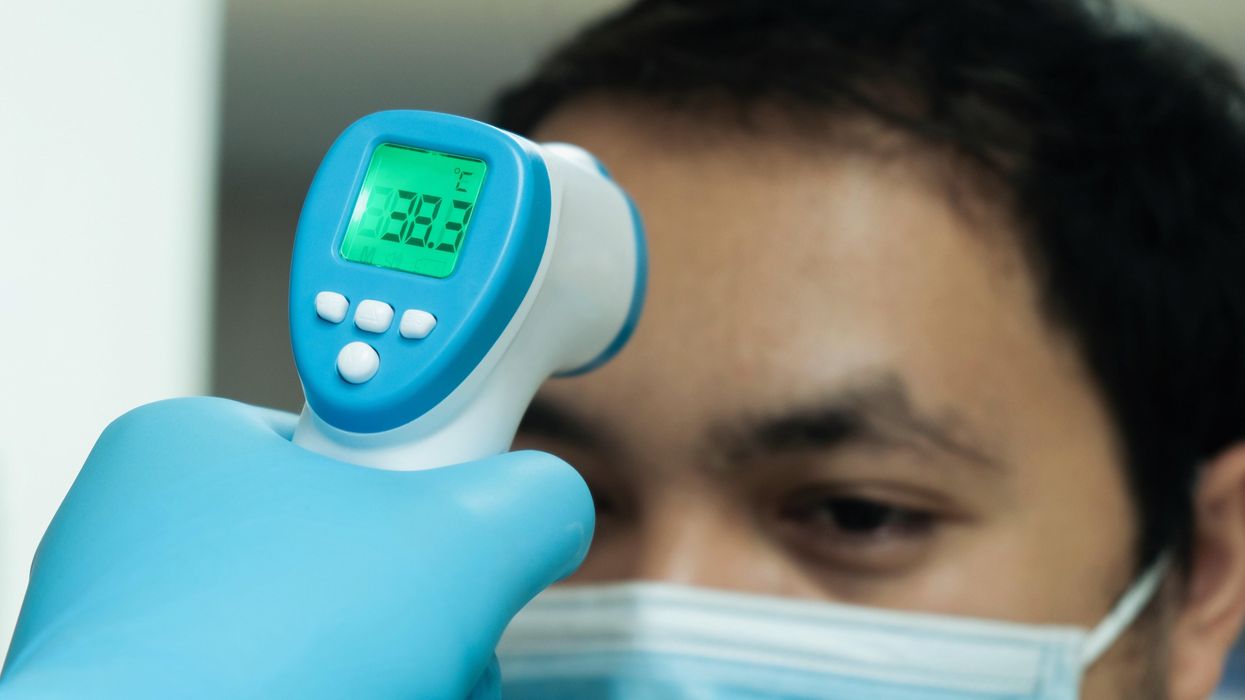 A person getting their temperature checked with a forehead thermometer.
