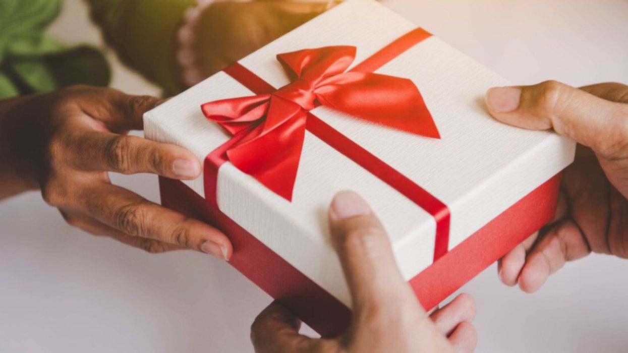 A person handing another person a Christmas present.